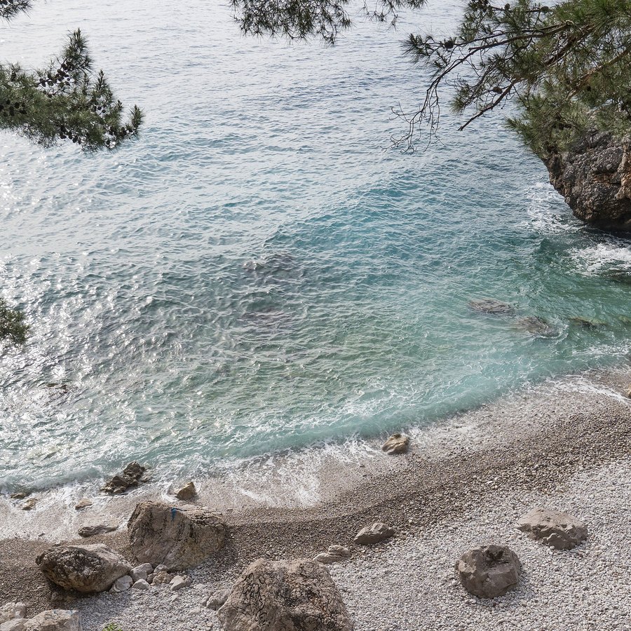 Türkisfarbenes Wasser und heller Kiesstrand in der Bucht von Ratac bei Bar